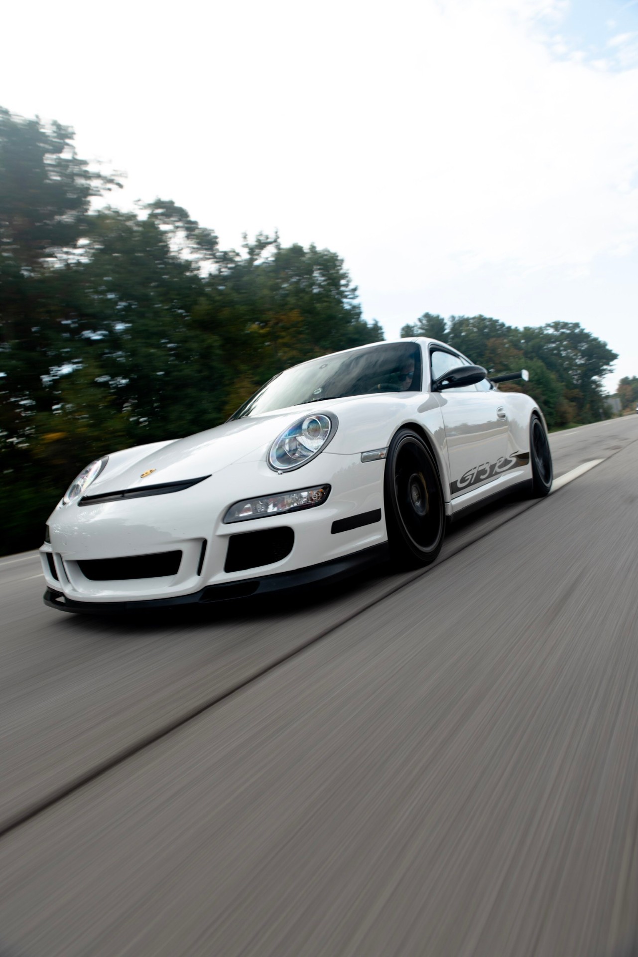 A white Porsche 911 GT3 RS at speed on an open road